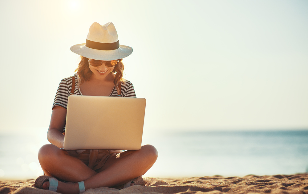 young woman working with laptop on nature in beach